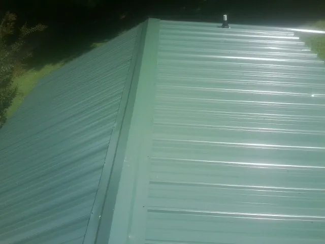 New green metal panels meeting at the ridge of a roof — Flat Roof Repair work by our crew in Richland