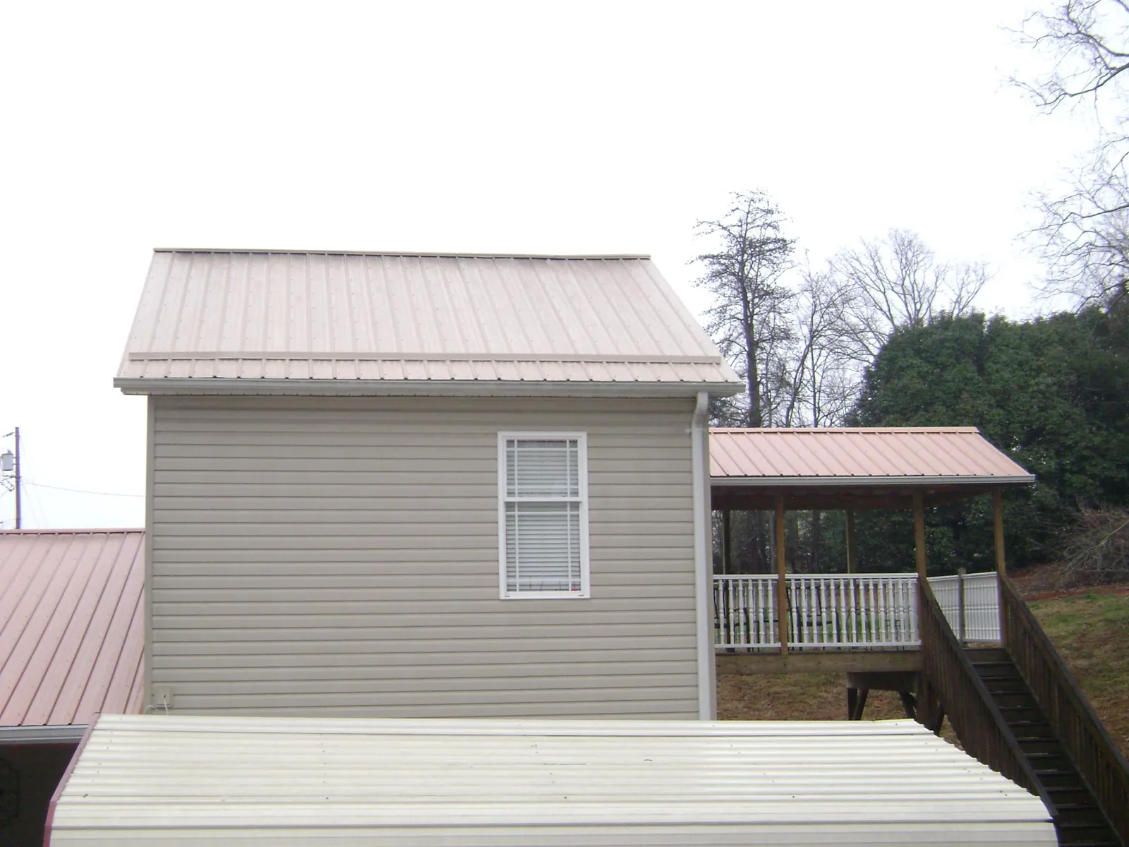 Tan metal roofs on a two story addition and attached porch, from a Roof Replacement job in Richland